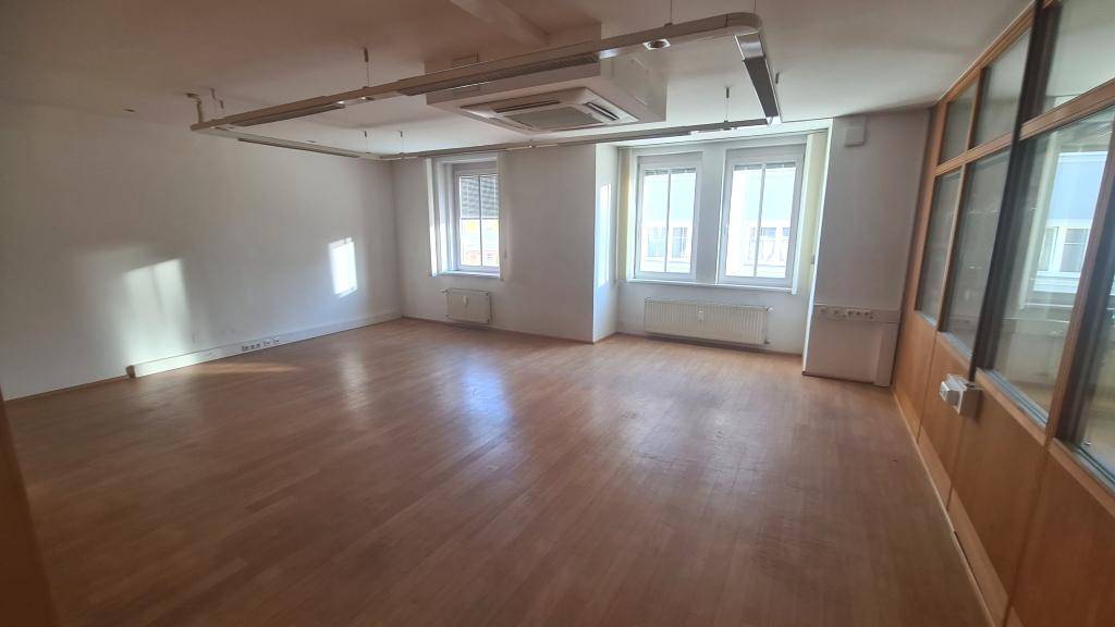 Helles Büro mit Holzboden, großen Fenstern und Klimaanlage, bietet viel Tageslicht.