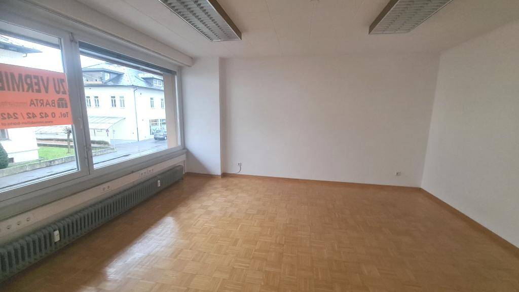 Geräumiger Büroraum mit großen Fenstern und Parkettboden, bereit zur Vermietung und gut beleuchtet.
