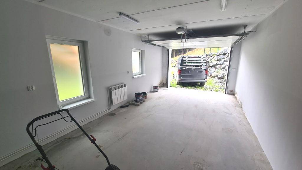 Geräumige Garage mit Betonboden, zwei Fenstern und direktem Zugang ins Freie.