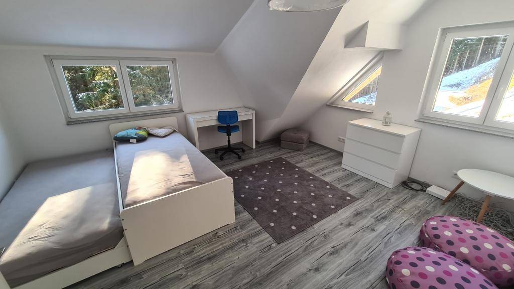 Kinderzimmer im Dachgeschoss mit Schrägen, Holzboden und zwei Betten.