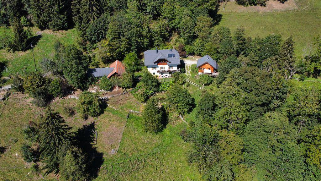 Nahaufnahme aus der Luft zeigt das Haupthaus mit zwei Nebengebäuden, umgeben von üppiger Vegetation.