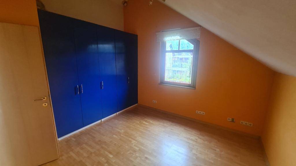 Schlafzimmer mit Holzparkettboden, blauen Einbauschränken und Fenster.