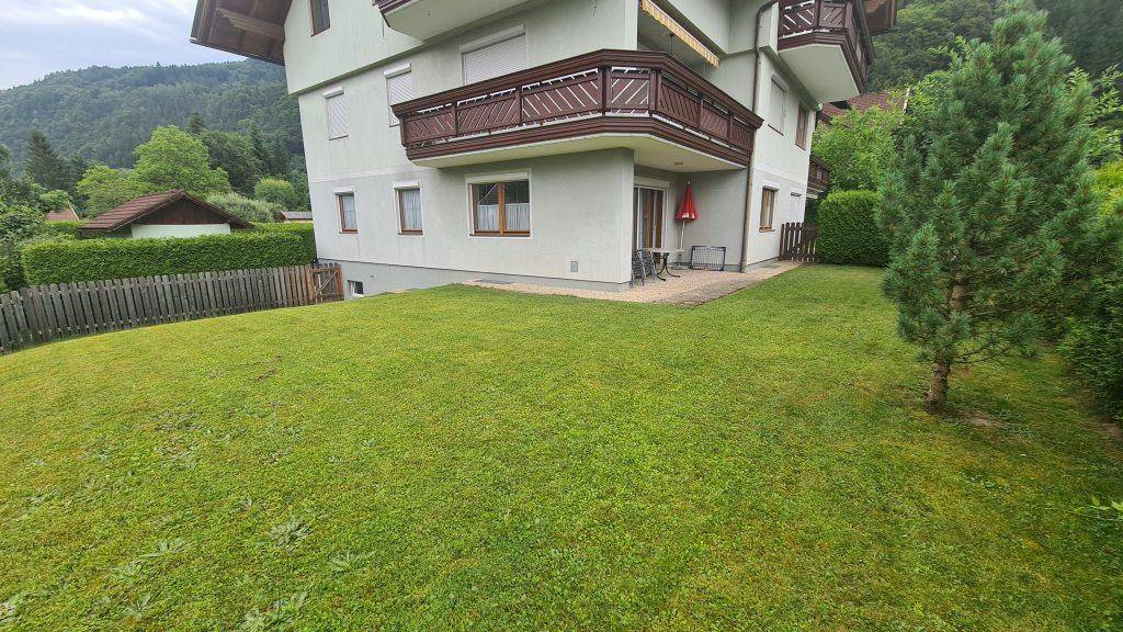 Weitläufiger Rasenbereich mit angrenzender Terrasse und Blick auf die umliegende Natur.