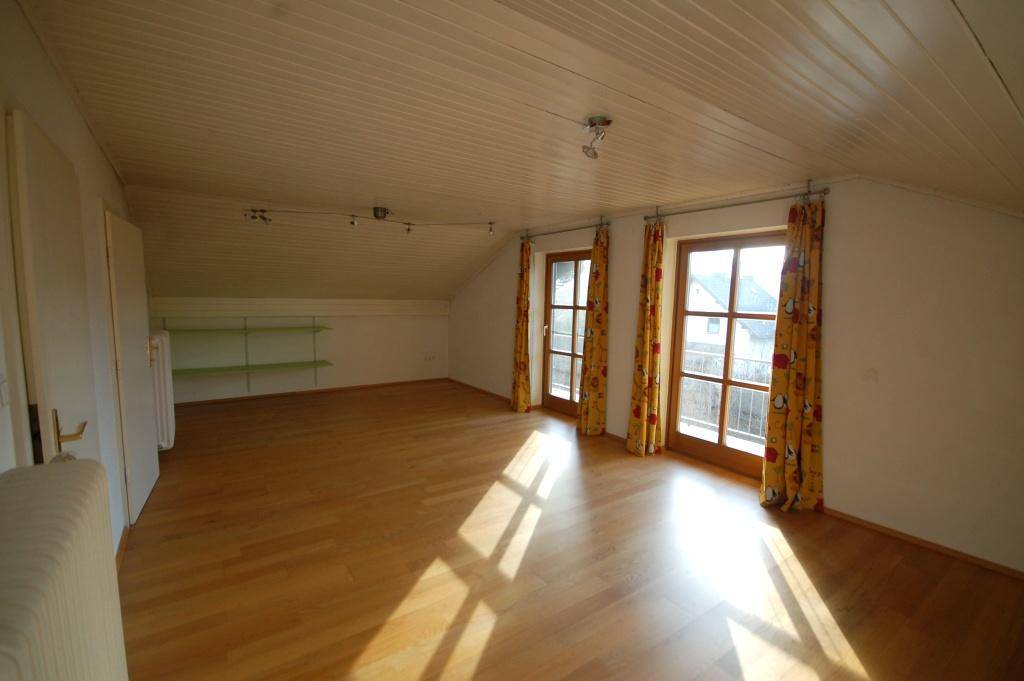 Geräumiges Dachzimmer mit Holzboden, Holzdecke und Zugang zu einem französischen Balkon.