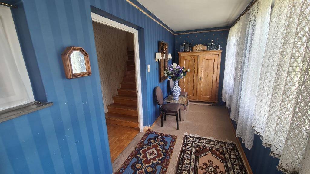 Flur mit blauer Streifentapete, Teppichläufern und Holztreppe im Hintergrund.