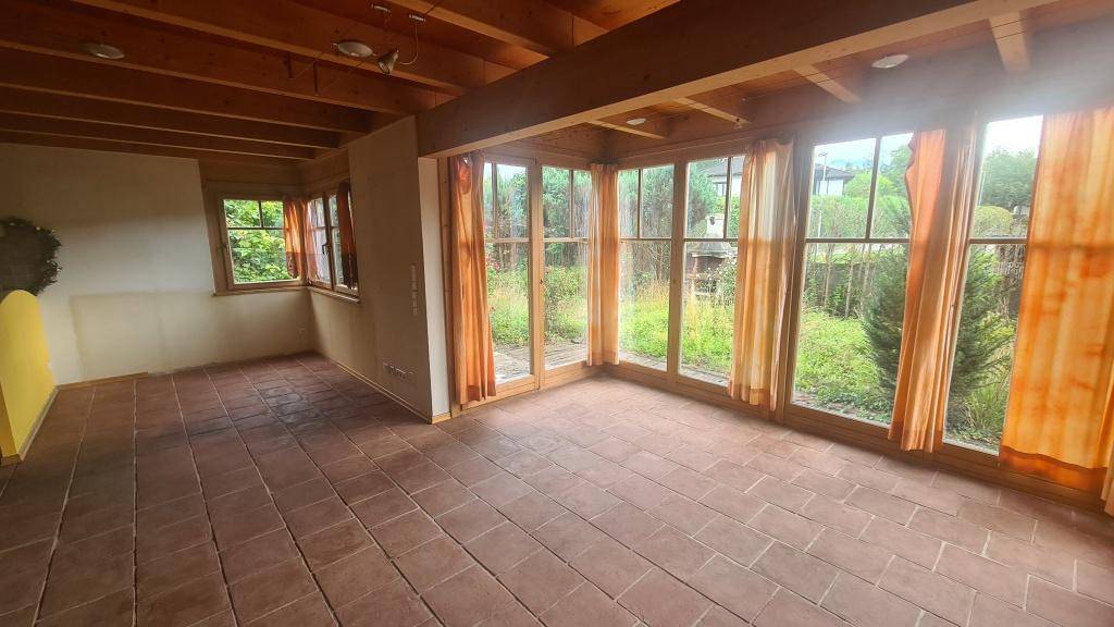 Offener Wohnbereich mit Terrakotta-Fliesenboden, Holzdecke und Zugang zur Küche.