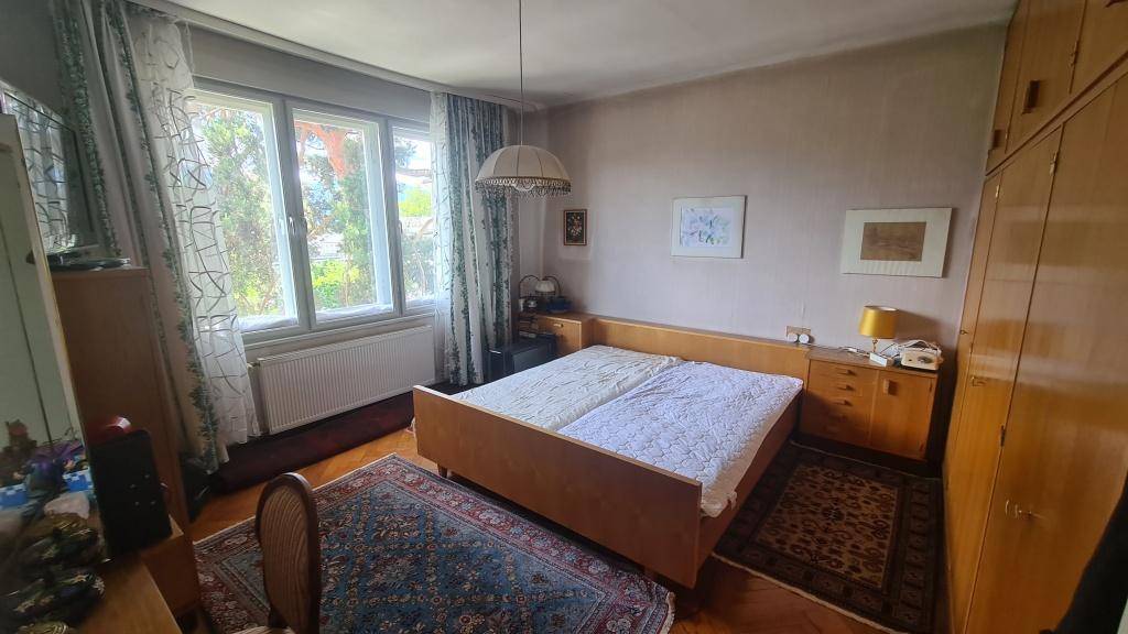 Schlafzimmer mit Doppelbett, Teppichboden und großem Fenster, hell und geräumig.