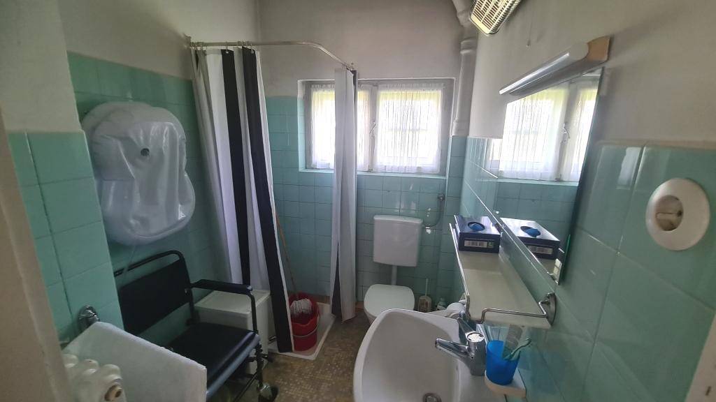 Badezimmer mit mintgrünen Fliesen, Dusche und Fenster, im Stil der 80er Jahre.