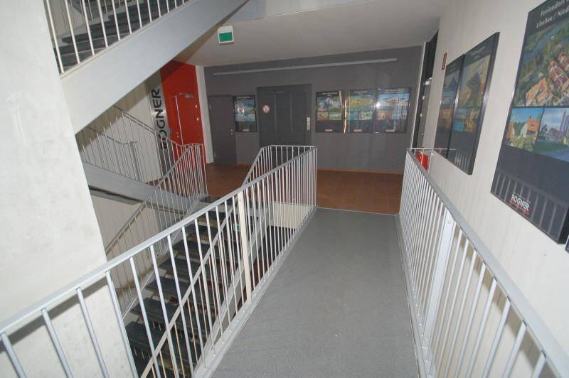 Geräumiges Treppenhaus mit Metallgeländern und breiten Stufen, das eine klare und funktionale Verbindung zwischen den Etagen bietet.