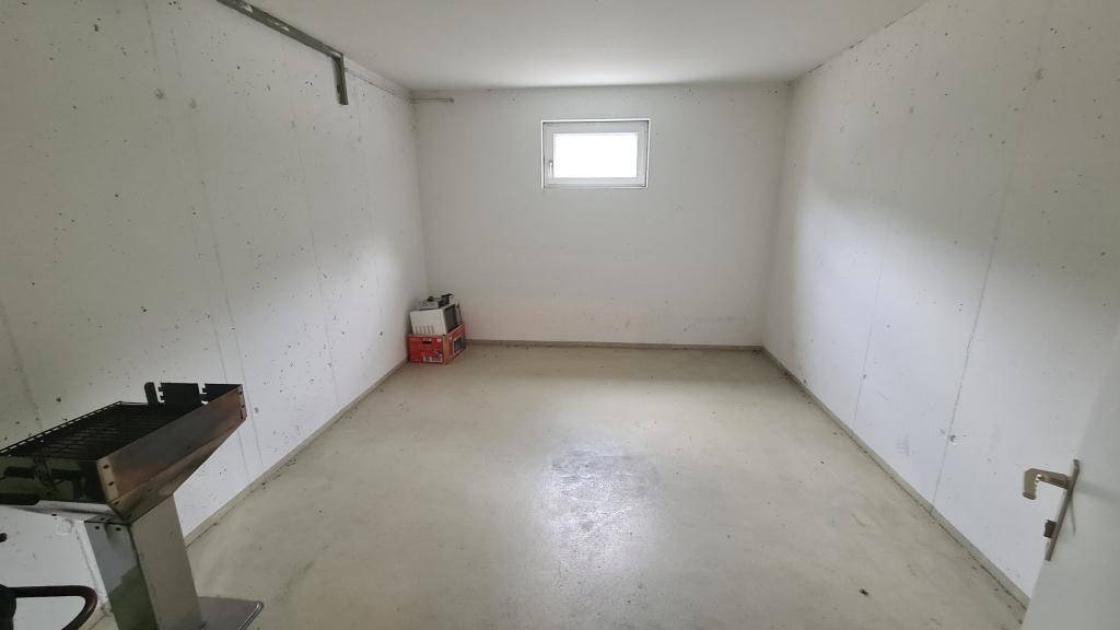 Einfacher Abstellraum im Kellergeschoss mit Betonboden und kleinem Fenster.