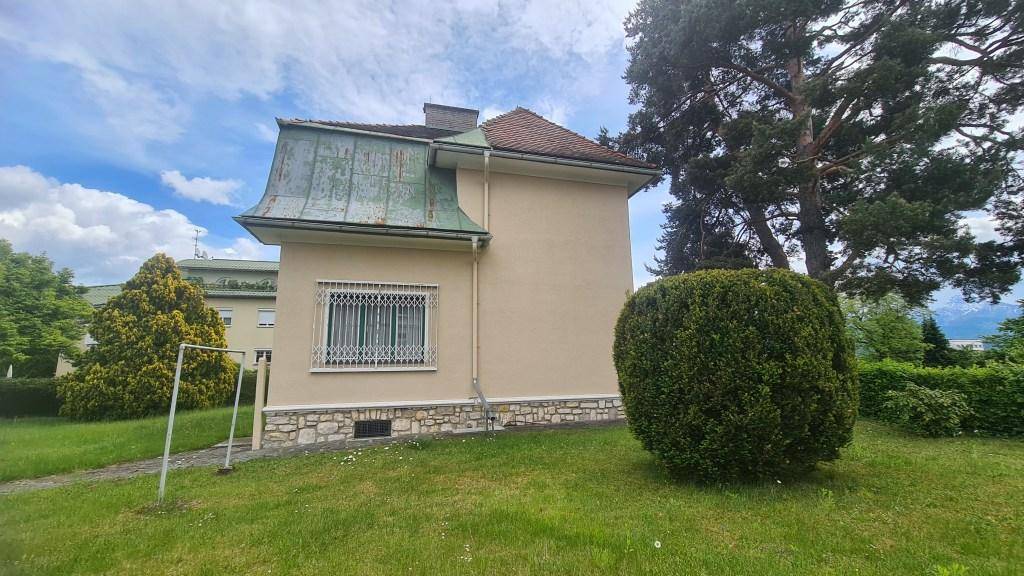 Rückansicht des Hauses mit großem Garten, alten Bäumen und einem Fenster mit Gitter.