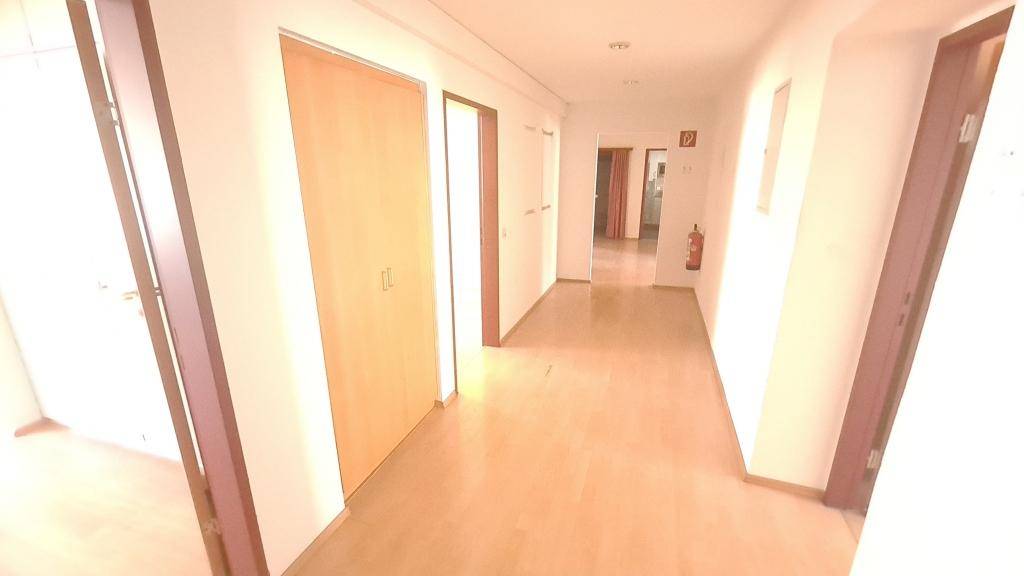 Langer Flur mit Holzboden und mehreren Türen, der verschiedene Büroräume verbindet.