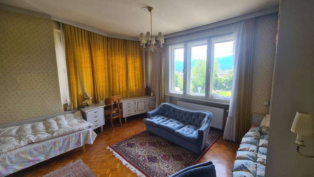 Helles Wohnzimmer mit Parkettboden, blauer Couch und Blick ins Grüne.