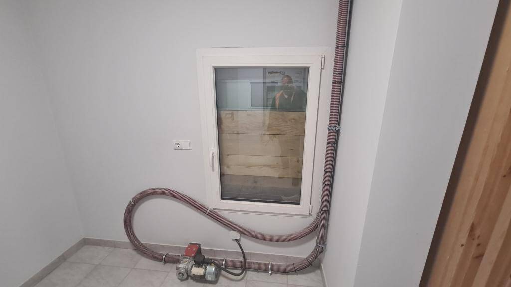 Kleiner Technikraum mit Fenster, Pumpe und Schlauchsystem am Boden.