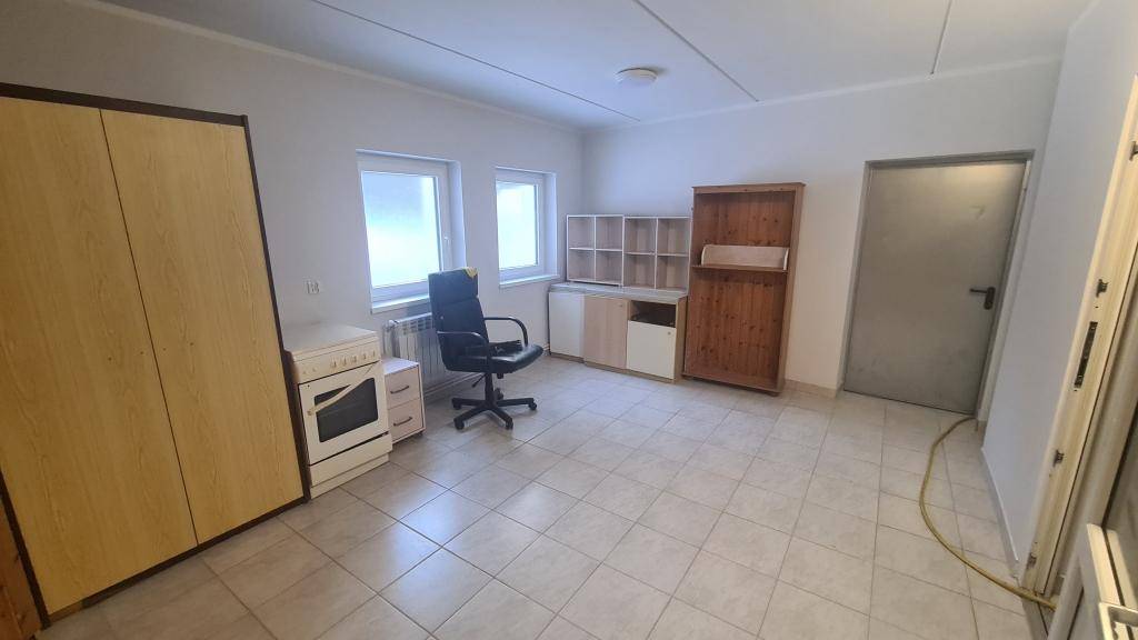 Geräumiges Zimmer mit Fliesenboden, Schrank, Schreibtisch und zwei Fenstern.