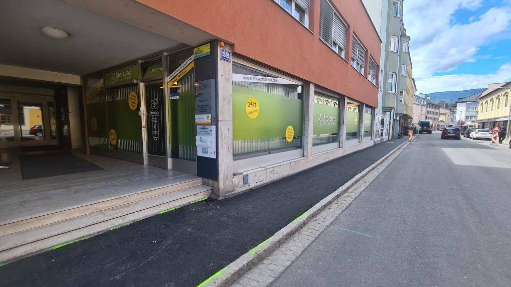 Gebäudefassade mit großen Schaufenstern eines Geschäfts an einer belebten Straße.