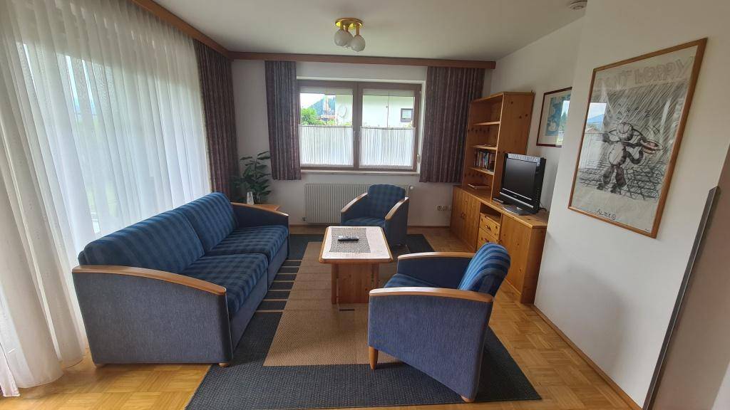 Helles Wohnzimmer mit traditioneller Einrichtung, Parkettboden und Blick ins Grüne.