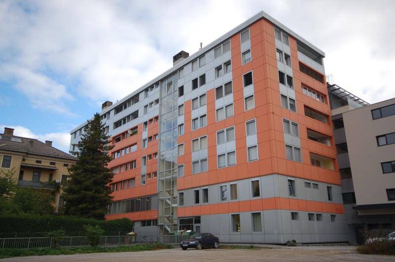Großes Wohn- und Geschäftsgebäude mit markanter orange-grauer Fassade und vielen Fenstern.