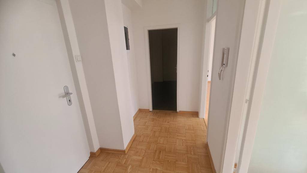 Heller Flur mit Parkettboden und weißen Wänden, der zu verschiedenen Räumen führt und gut gepflegt ist.