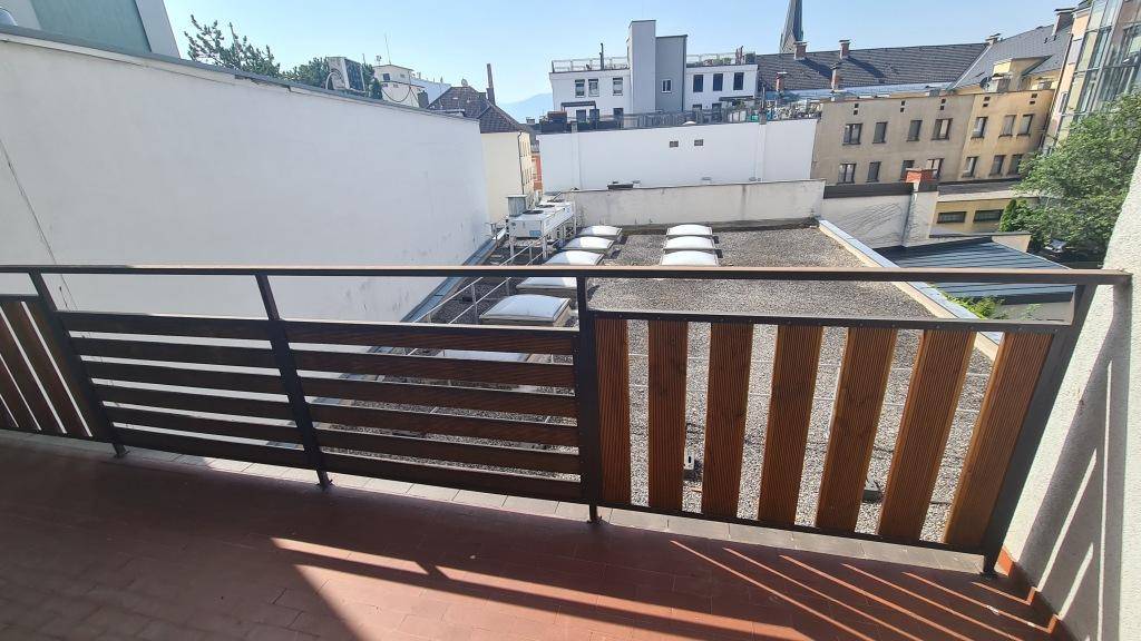 Balkon mit Holz- und Metallgeländer, bietet einen weiten Blick über die Dächer der Stadt.