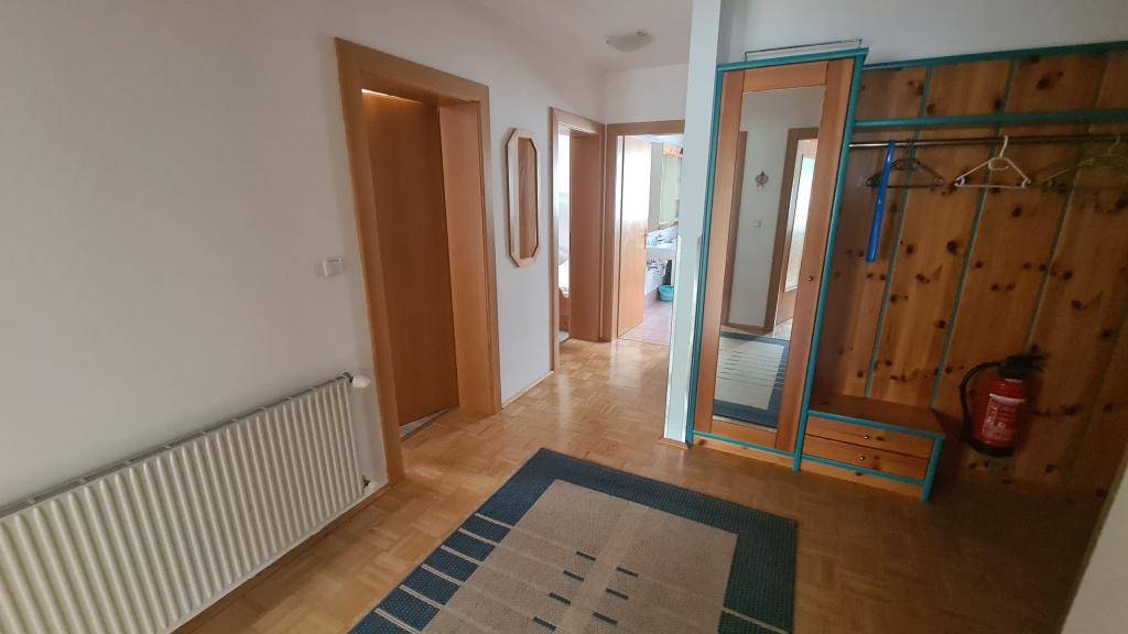 Heller Flur mit Parkettboden, Garderobe und Spiegel, führt zu weiteren Räumen.