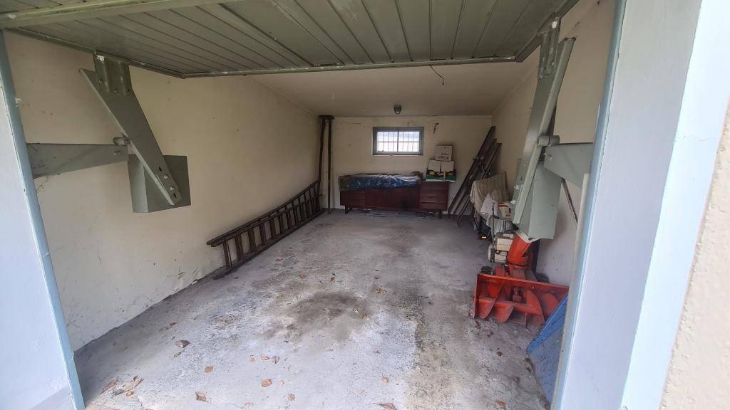 Innenansicht der Garage mit Betonboden, Fenster und Stauraum für Geräte.