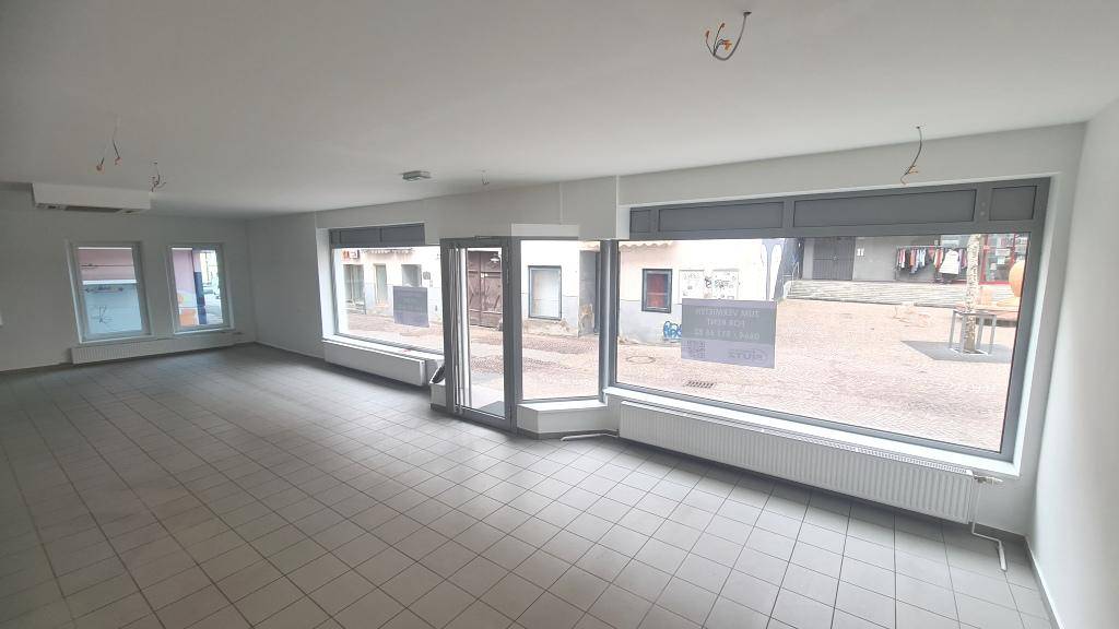 Weitläufiger, heller Ladenraum mit großen Schaufenstern und Blick auf die Straße, ideal für Einzelhandel.
