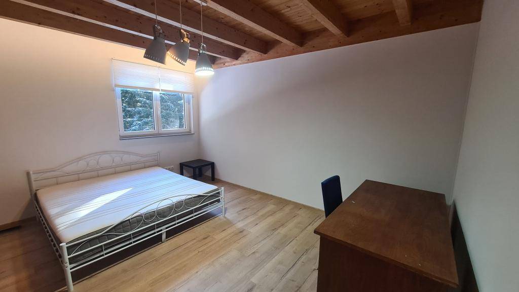 Geräumiges Schlafzimmer mit Holzbalken, Holzboden und einem komfortablen Doppelbett.