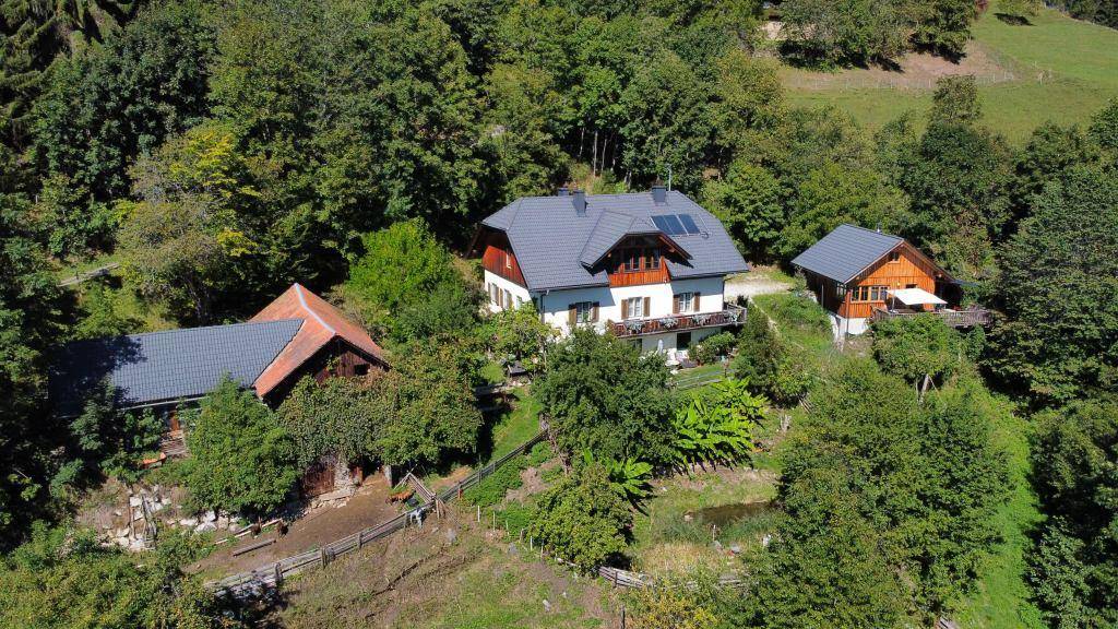 Luftaufnahme des Anwesens mit Haupthaus und Nebengebäuden, eingebettet in eine grüne Hügellandschaft.