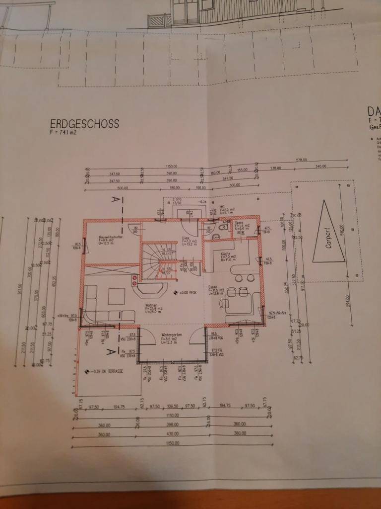 Grundriss des Erdgeschosses mit Wohnbereich, Küche, Bad und Carport-Stellplatz.