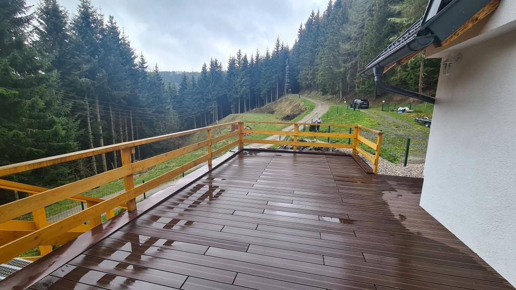 Große Holzterrasse mit Geländer und einem weiten Blick auf den umliegenden Wald.