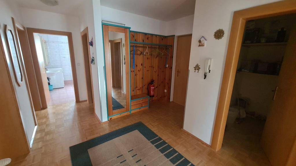 Geräumiger Eingangsbereich mit Holzgarderobe und Parkettboden, bietet viel Stauraum.