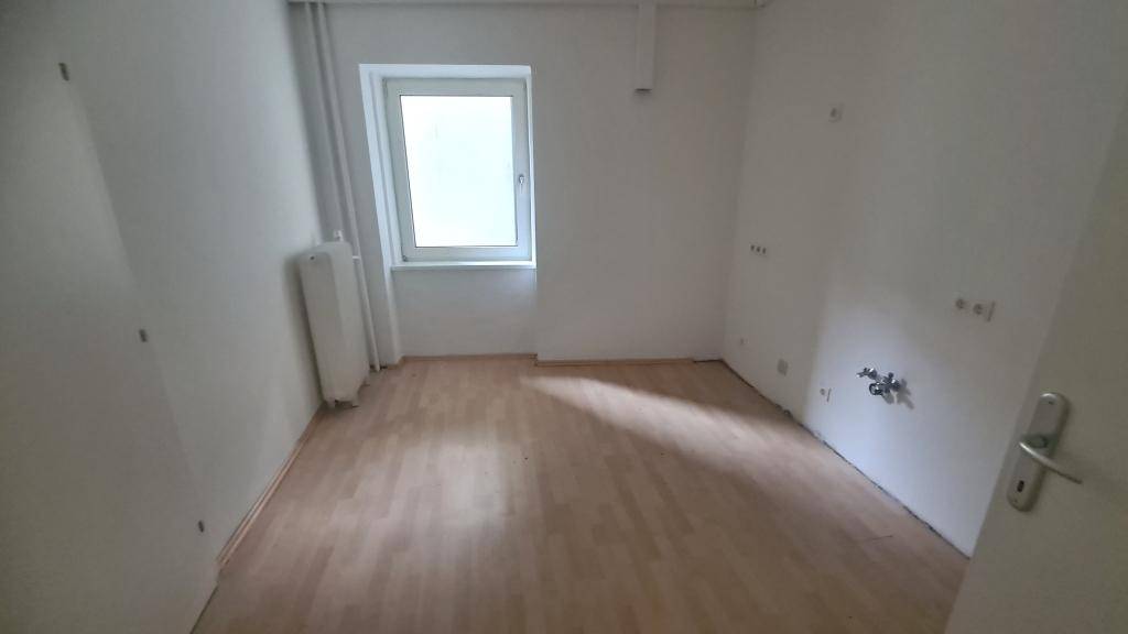 Kleiner Raum mit Laminatboden, einem Fenster und Heizkörper, ideal als Büro oder Abstellraum.