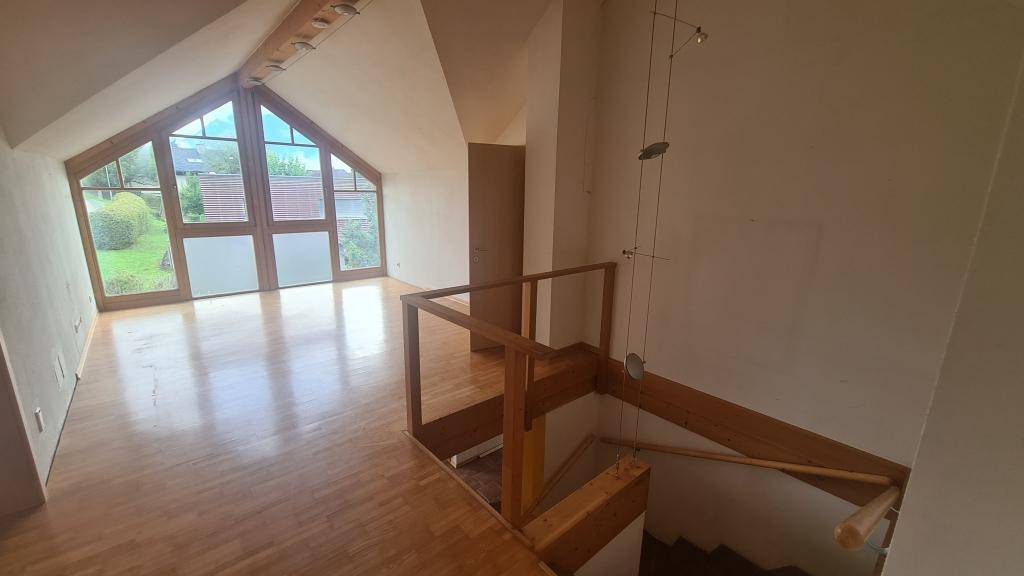 Heller Raum im Obergeschoss mit Holzparkettboden und großen Giebelfenstern.