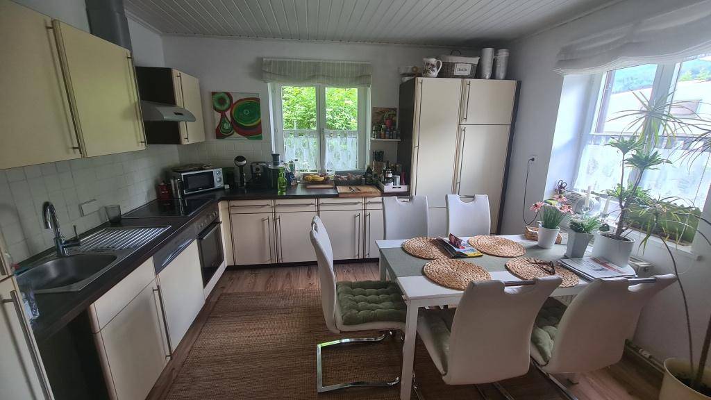 Helle Wohnküche mit beigen Schränken, Esstisch und Blick ins Grüne.
