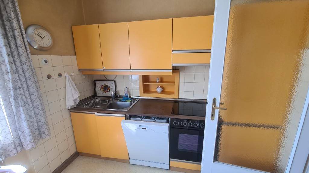 Küche mit orangefarbenen Schränken, Spülmaschine und integriertem Backofen.