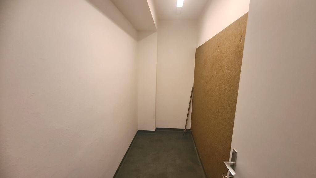 Schmaler Abstellraum mit dunklem Boden und weißen Wänden, bietet zusätzlichen Stauraum für diverse Gegenstände.