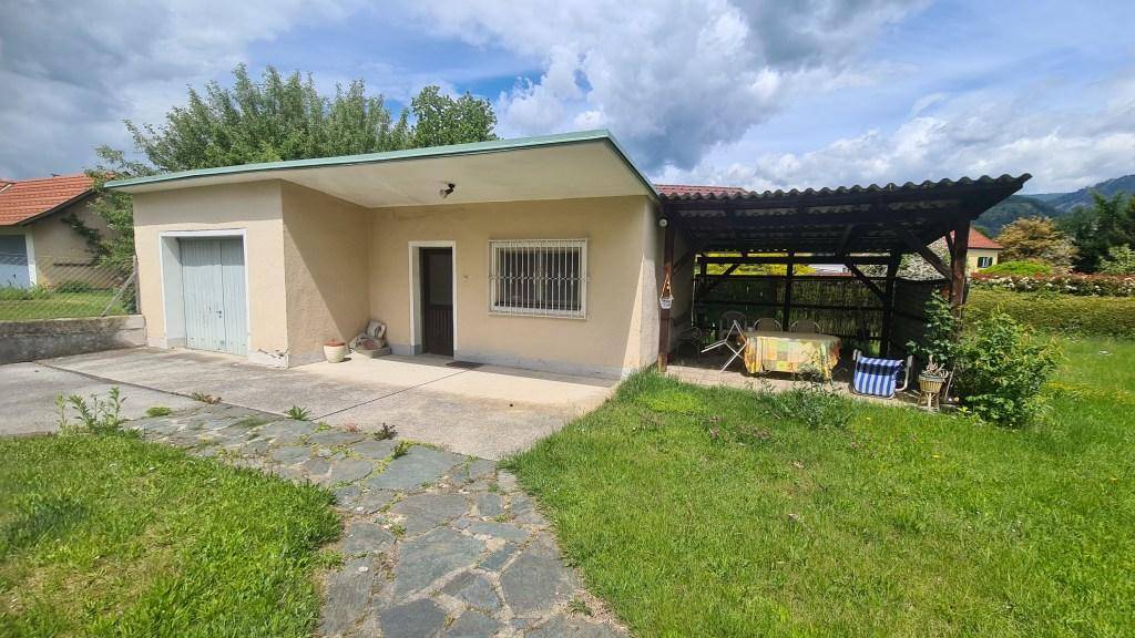 Freistehende Garage mit Carport und überdachtem Sitzbereich im Garten.
