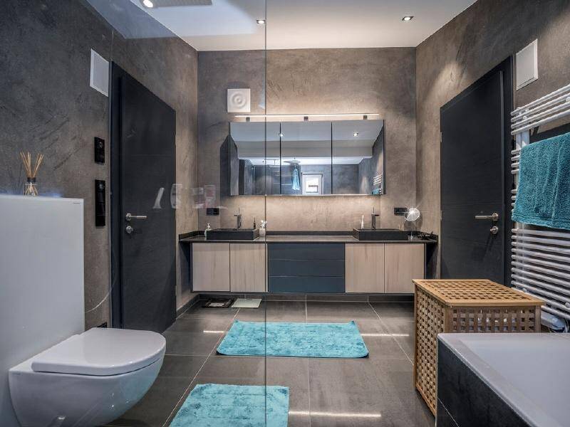 Modernes Badezimmer mit Doppelwaschbecken, dunklen Fliesen und beheiztem Handtuchhalter.