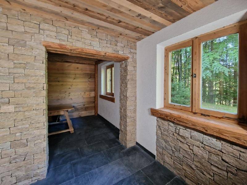 Flur mit Steinwänden, Holzdecke und Zugang zu einem holzvertäfelten Raum, der als Sauna dient.