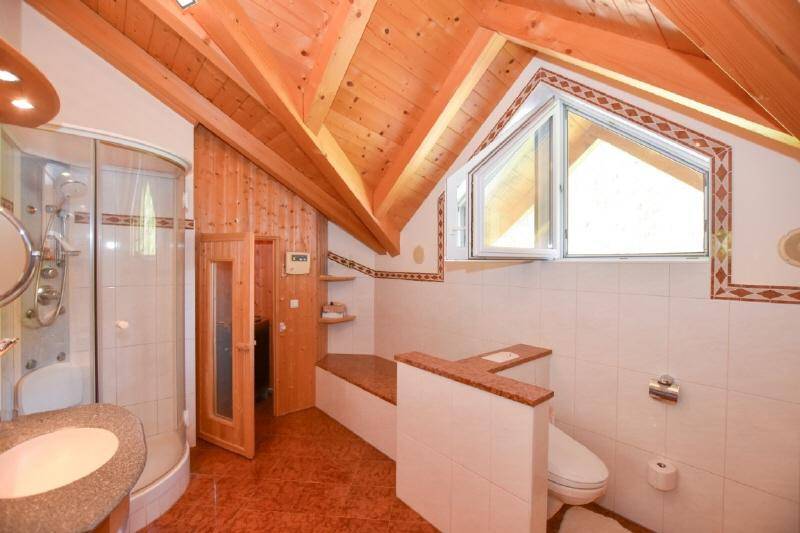 Badezimmer mit Dusche, WC, Waschbecken und Holzbalkendecke sowie integrierter Sauna.
