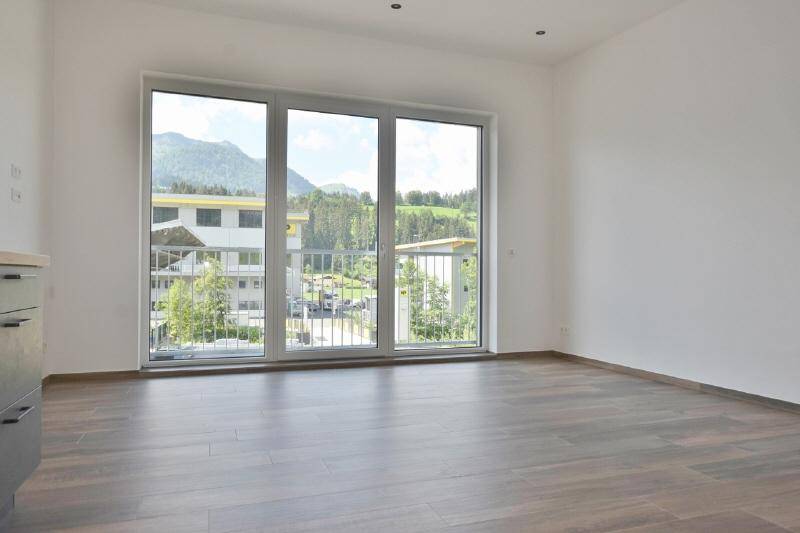 Lichtdurchfluteter Wohnraum mit weitem Blick auf die umliegende Berglandschaft und viel Grün.