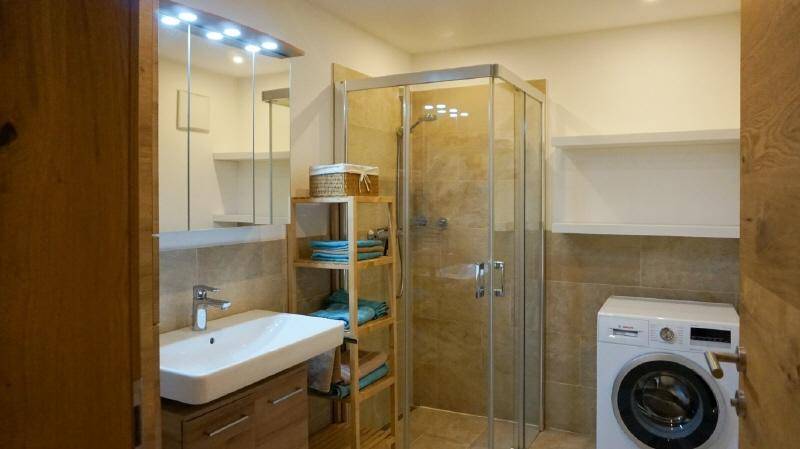 Modernes Badezimmer mit Duschkabine, Waschbecken und integrierter Waschmaschine.