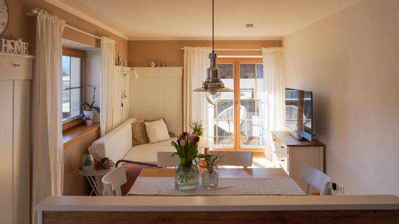 Gemütlicher Wohnbereich mit Esstisch, Sofa und Blick auf den Balkon durch die Terrassentür.