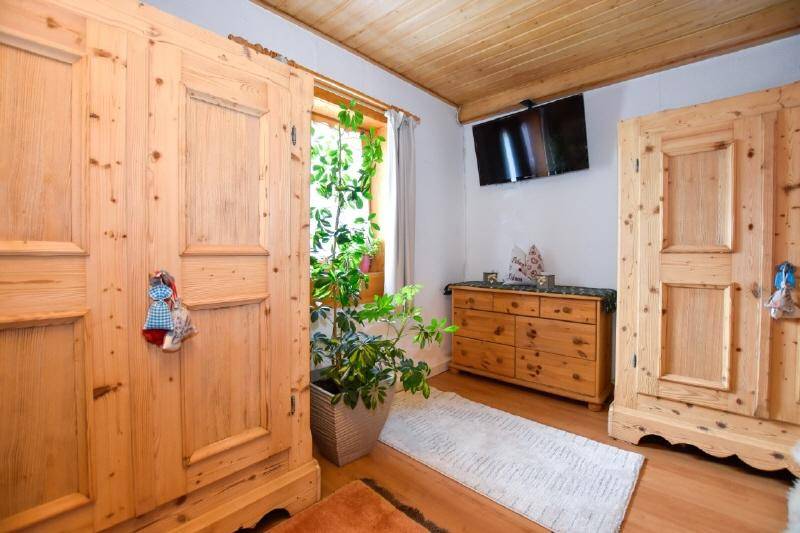 Schlafzimmer mit rustikalen Holzschränken, Kommode und einem an der Wand montierten Fernseher. 