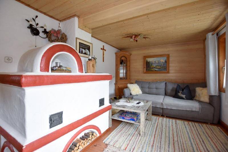 Gemütliches Wohnzimmer mit einem großen, traditionellen Kachelofen und Holzbalkendecke. 