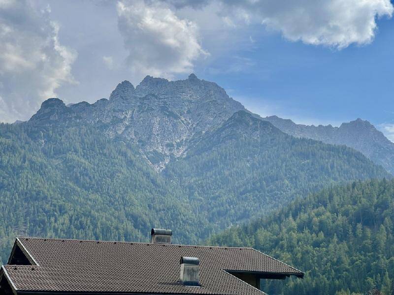 Beeindruckender Blick auf die majestätische Bergkette über einem traditionellen Hausdach.
