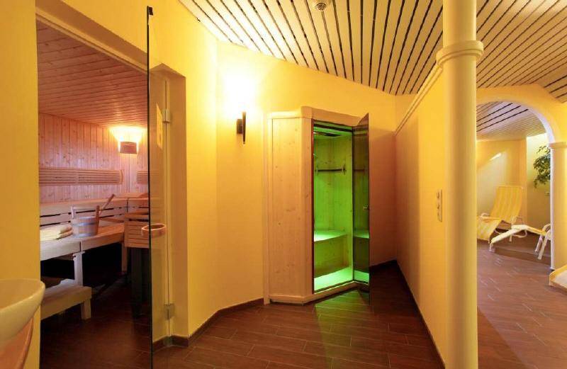 Einladender Wellnessbereich mit einer holzverkleideten Sauna, gefliestem Boden und einer besonderen Deckenkonstruktion.