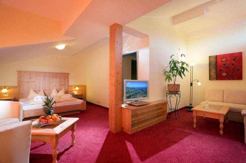 Gemütlicher kombinierter Schlaf- und Wohnbereich mit rotem Teppichboden, Holzmöbeln und einem Fernseher.