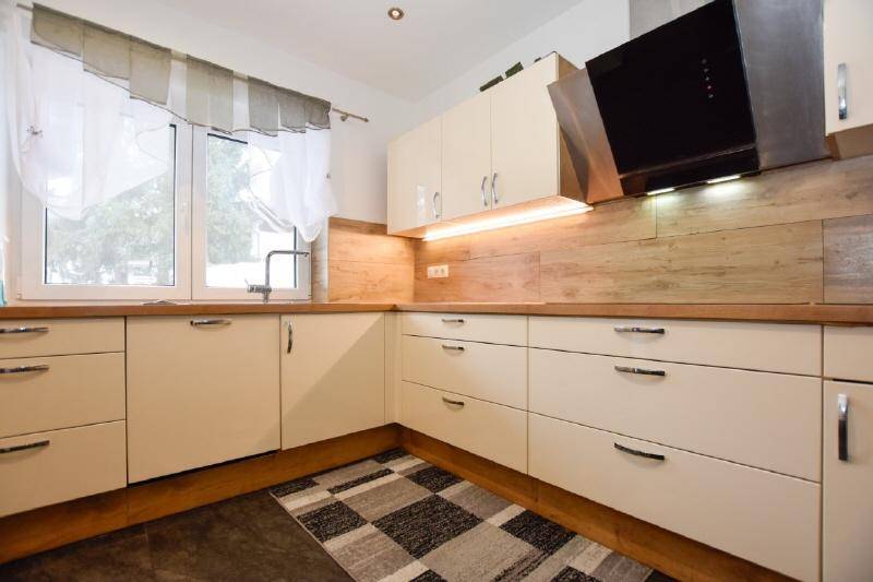 Helle Einbauküche mit cremefarbenen Fronten, Holz-Arbeitsplatten und Dunstabzugshaube.